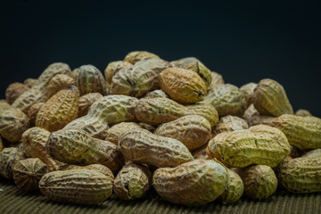 Peanuts in pile on light brown mat