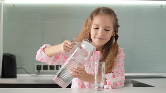 Child pours water from the carafe and drinks