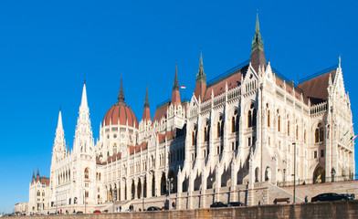 Daytime view of historical building of Hungarian Parliament, aka Orszaghaz, with typical symmetrical architecture and central dome on Danube River embankment in Budapest, Hungary, Europe. It is