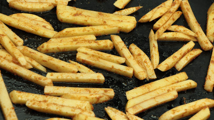 Uncooked french fries with spices on baking pan