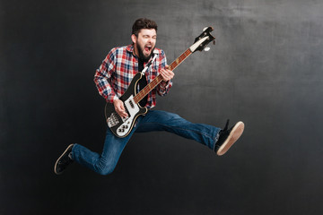 Screaming man jumping and playing on the guitar