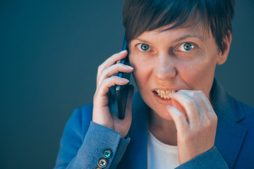 Nervous businesswoman bites fingernails during telephone convers