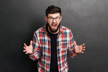 Furious irritated young man in glasses standing and screaming