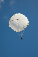 White round parachute on background blue sky.