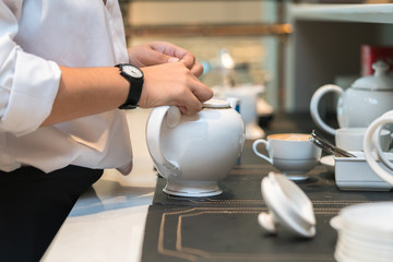 The waitress is pouring tea in the restaurant
