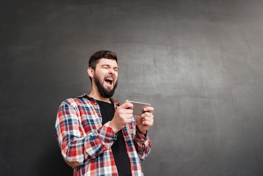 Man playing at phone over chalkboard
