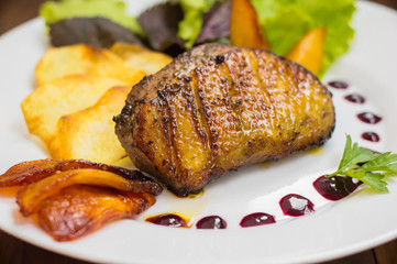 Duck breast with potato chips, herbs, sauce and caramelized apples. Wooden rustic table. Top view. Close-up