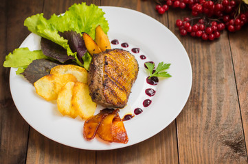 Duck breast with potato chips, herbs, sauce and caramelized apples. Wooden rustic table. Top view. Close-up