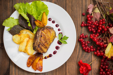 Duck breast with potato chips, herbs, sauce and caramelized apples. Wooden rustic table. Top view. Close-up