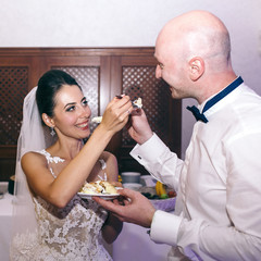 Newlyweds reach to each other faces forks with cake
