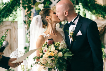 Bride and groom kiss with passion after wedding ceremony