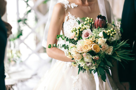 Elegant bride with white skin holds gorgeous wedding bouquet