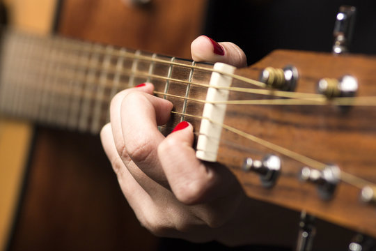 Young woman clamped with fingers guitar strings