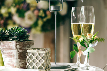Champagne flutes decorated with tiny roses stand on table with w