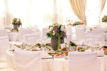 Flowerpot stands in the middle of rich served dinner table