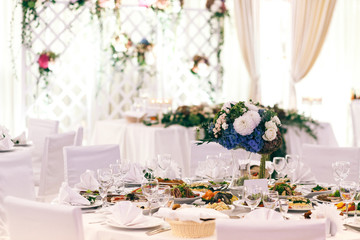Bouquet of white and blue flowers stands on white table in brigh