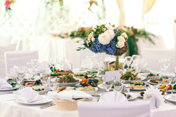 Bouquet of white and blue flowers stands on white table in brigh