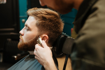 Image of man getting beard haircut at barbershop