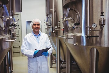 Smiling manufacturer writing while standing at brewery
