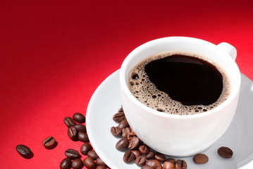 cup of coffee with coffee beans on a red background