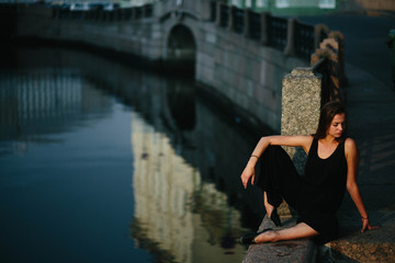young and graceful woman sitting near the river alone