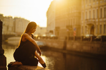 young and graceful woman sitting near the river alone