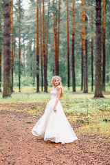 Obraz na płótnie Canvas Bride in wedding dress walking in the forest. Bride waiting for groom.