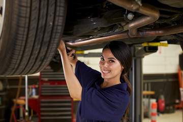 Obraz na płótnie Canvas Portrait Of Female Auto Mechanic Working Underneath Car