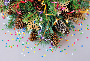 Spruce branches with cones and Christmas decorations: snowflakes, streamers and confetti.