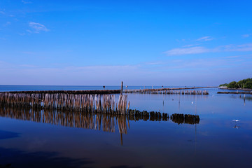 Long simple wooden jetty leading into blue ocean in the gulf of Thailand with sunset
