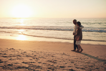 Senior couple strolling on the beach at sunset