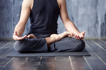 Young men do yoga indoors on black mat