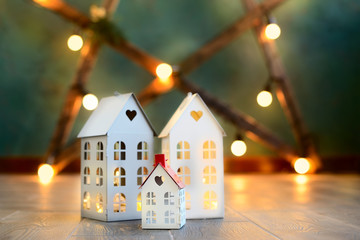 little toy Christmas houses with a burning light inside is on blured green background