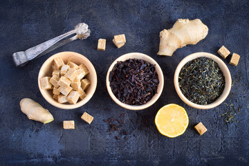 Wooden bowls with black and green tea and sugar, top view
