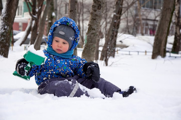 Fototapeta na wymiar Cute litle boy shoveling snow