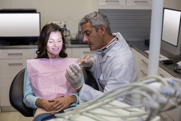Dentist showing mouth model to female patient