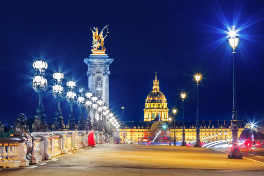 Fototapeta Alexandre III Bridge, Paris France. Night scene of cityscape with lights. Invalide palace at background.