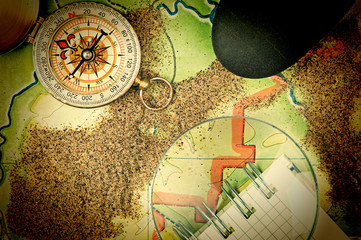 compass and  notebook on the map with sand