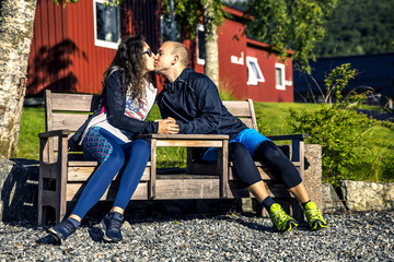 Plakat Happy couple sitting and kissing on the bench, Norway