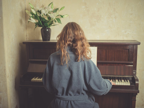 Woman in bathrobe playing piano