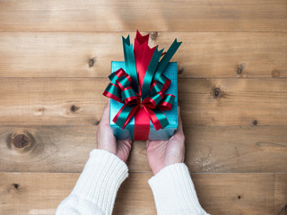 Creative hobby. Woman's hands wrap christmas holiday handmade present in craft paper with twine ribbon. Making bow gift box, decorated with cute object on wooden table, top view.flat lay composition