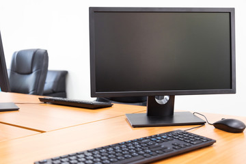 Blank monitor on wooden desktop in office room