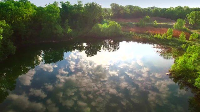 Amazing natural beauty, aerial flyover of pond in gravel pit reflecting sky.
