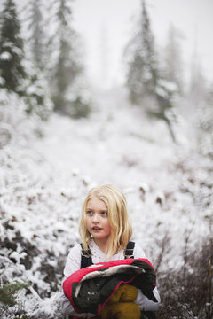 Young girl holding warm jacket in snow covered landscape