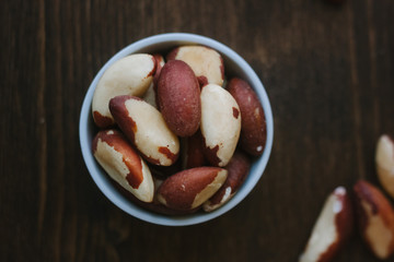 Brazil nuts on white ceramic bowl over the wooden table