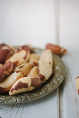 Brazil nuts in metal plate over the white wooden table.