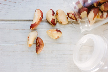 Brazil nuts and glass bottle over the white table