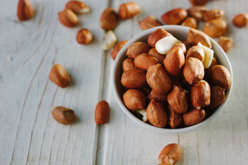 Dry peanuts in white bowl over the white table