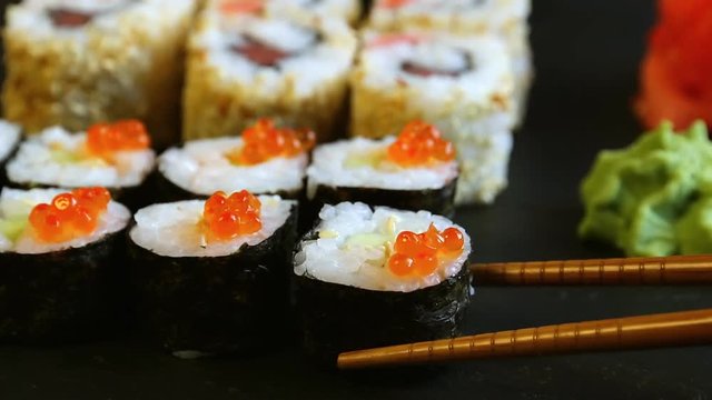chopsticks taking portion of sushi roll with red caviar