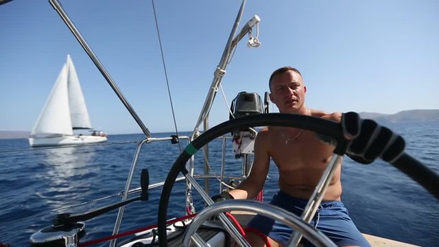 Young man skipper steers boat sailing during yacht regatta.